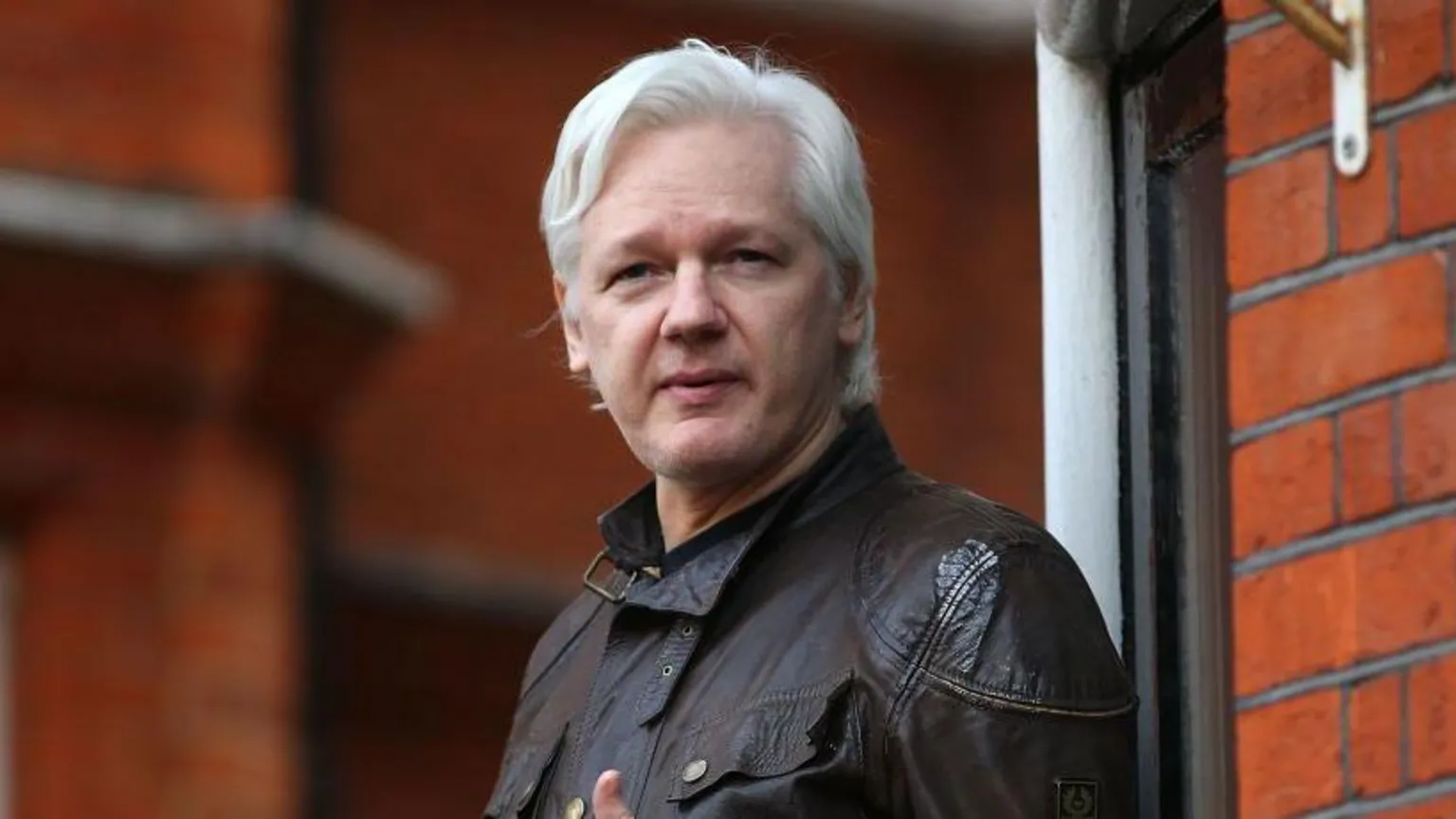 Julian Assange ao centro saindo de sua casa